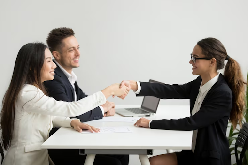 Smiling diverse businesswomen shaking hands in an interview.